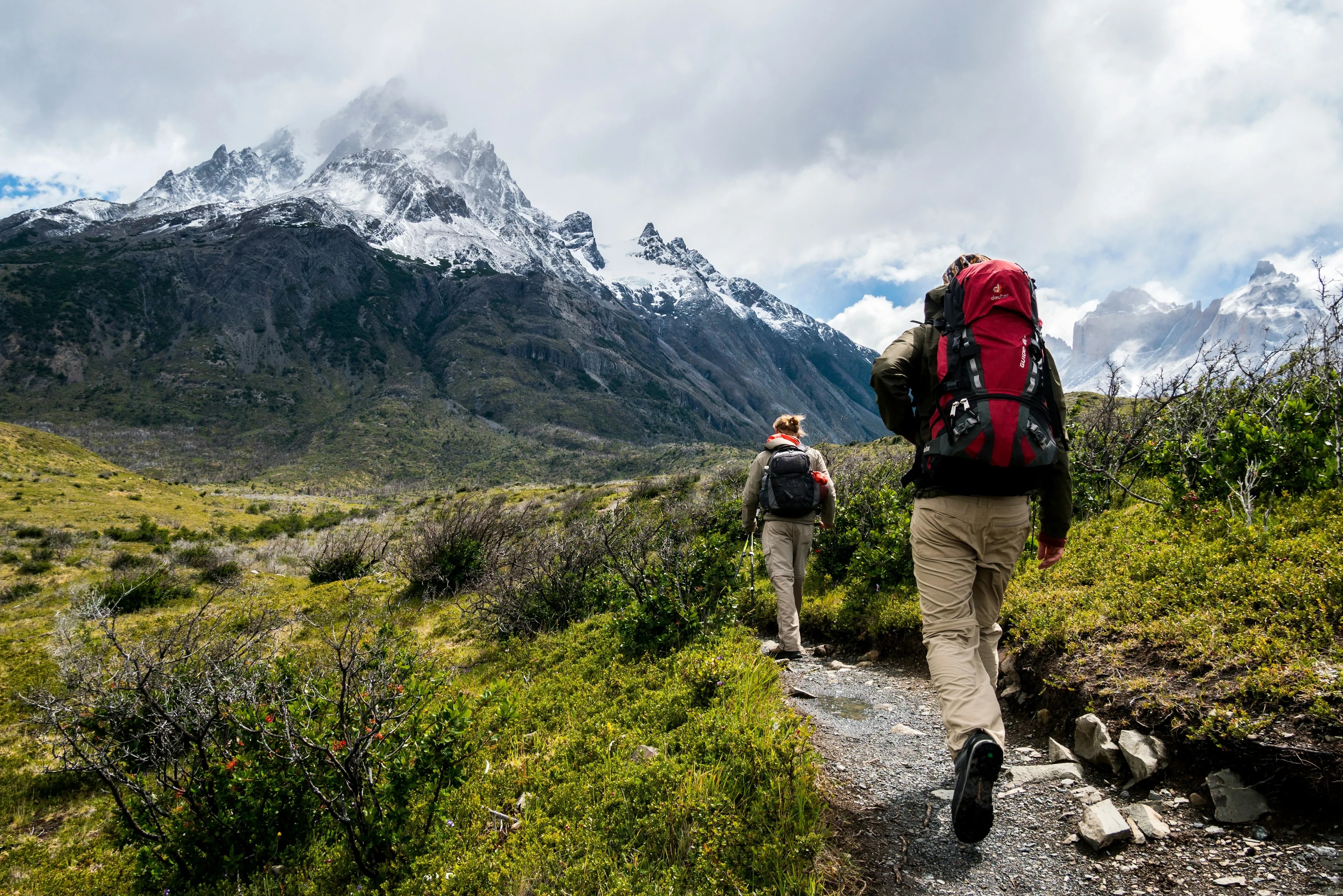 Two hikers heading toward snow-capped mountains